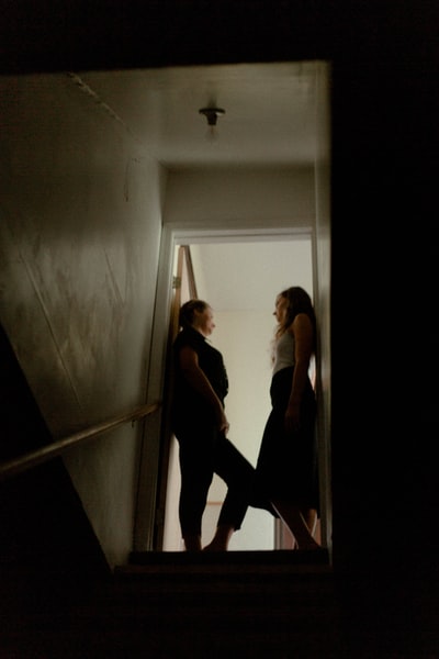 穿着黑色背心和黑色裤子的女人站在白色走廊上